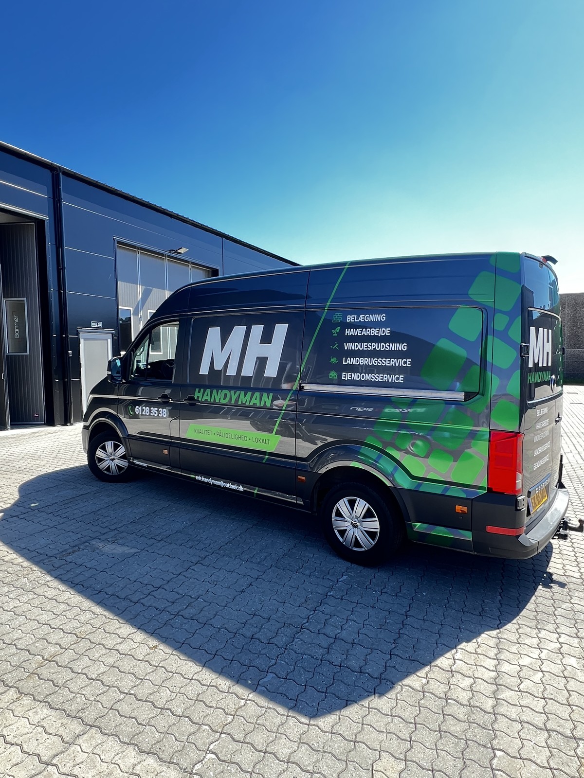 MH Handyman sort varevogn med grønt mønster, logo og ydelser på siden