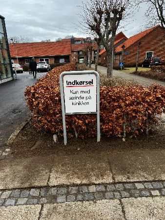 Indkørsel way-finding skilt ved klinikken med pil-anvisning